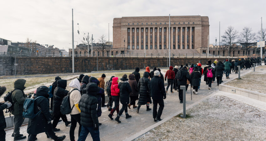 Kuvassa mielenosoittajien joukko marssii kohti Eduskuntataloa Helsingissä