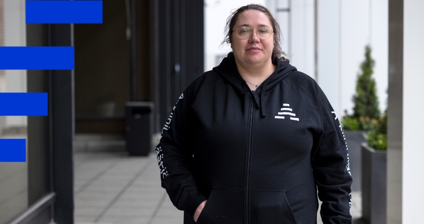 Kuvassa henkilö katsoo ulkona kameraan. Hänellä on silmälasit, vaaleat hiukset ja musta huppari, jossa lukee A-klinikkasäätiö